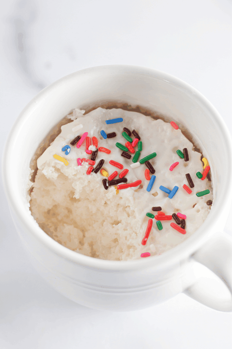 Air fryer angel food mug cake in a mug topped with whipped cream and berries