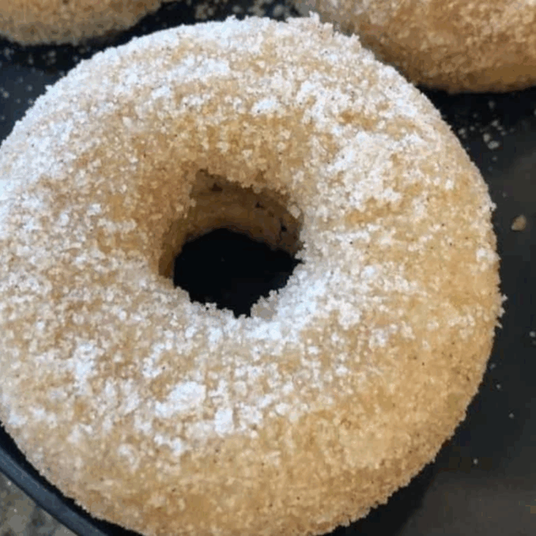 Soft, fluffy air fryer banana donuts on a plate, sprinkled with cinnamon sugar.