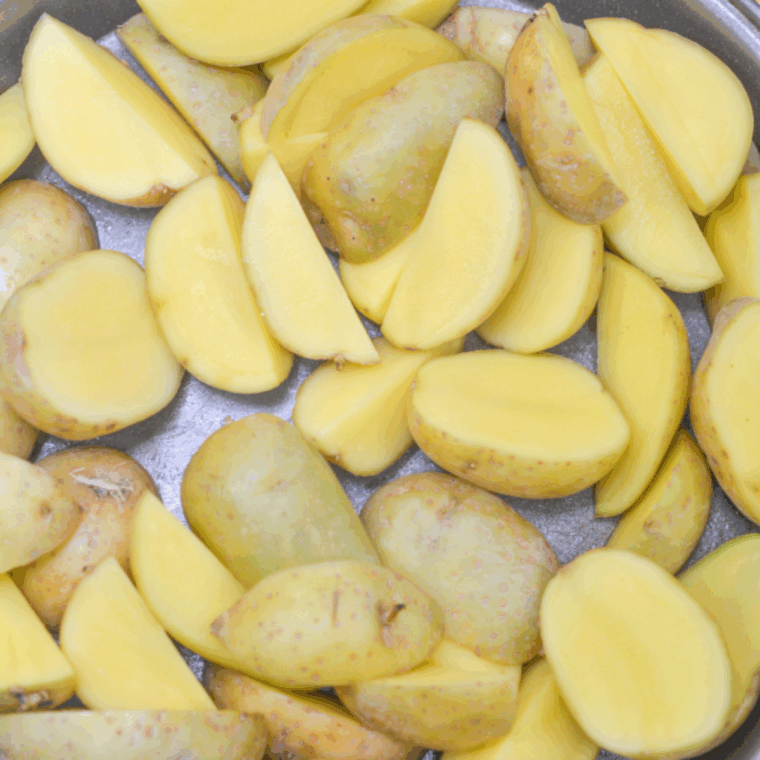 Washed and halved baby potatoes on a cutting board, dried with paper towels for even cooking.