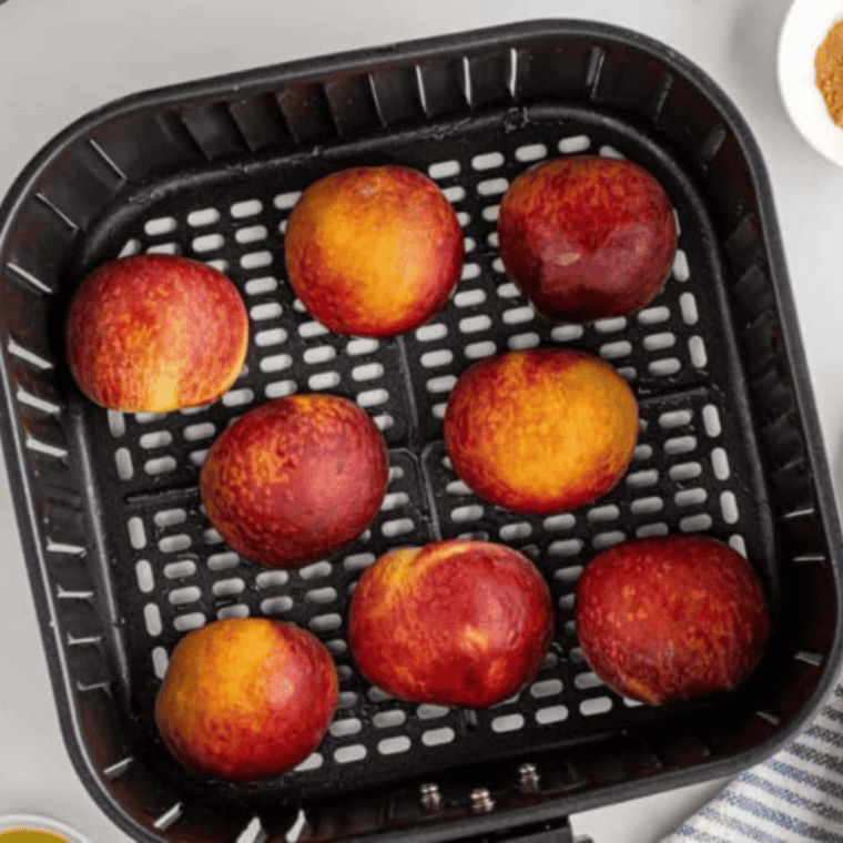 Peach halves placed cut-side down in air fryer basket cooking until tender