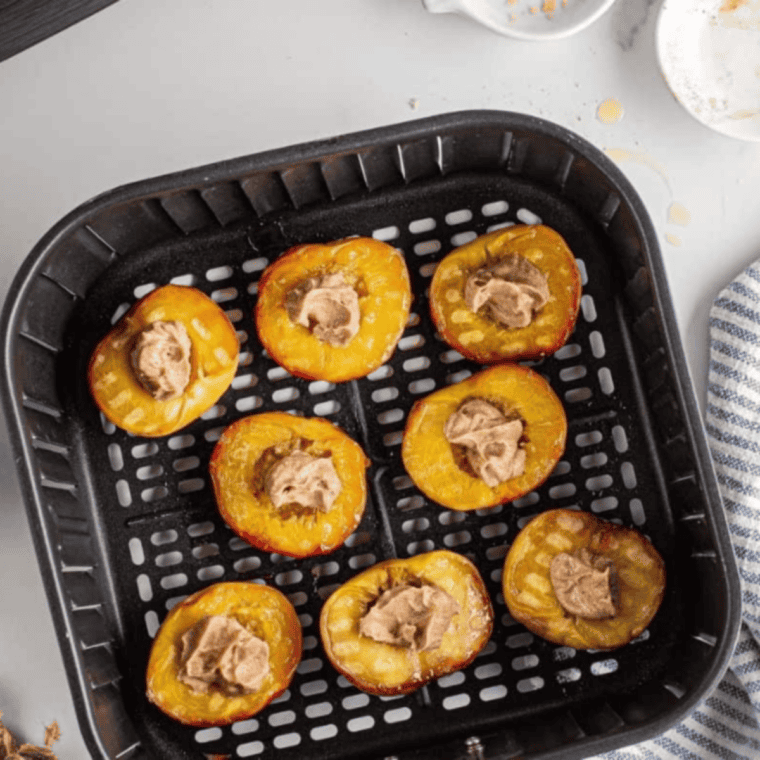 Flipping air fryer peaches and adding butter-sugar-cinnamon topping before finishing caramelization