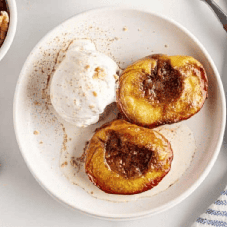 Plate of Easy Air Fryer Peaches With Brown Sugar and Cinnamon on kitchen table with ice cream on the side.