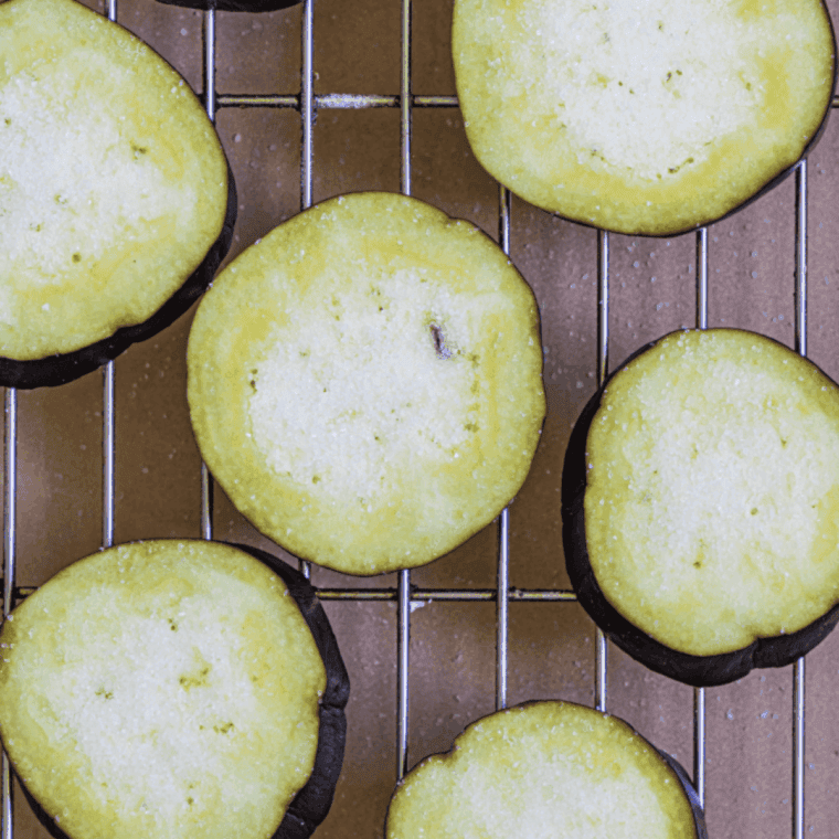 Salting sliced eggplant rounds on paper towels to remove excess moisture before cooking.