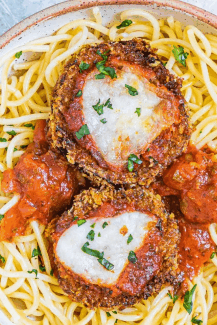 Crispy and cheesy Easy Cheesecake Factory Eggplant Parmesan served on a plate with marinara sauce and melted mozzarella.