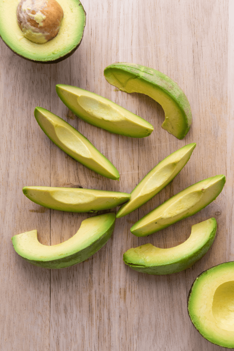 sliced avocado sticks being patted dry with paper towel for air frying