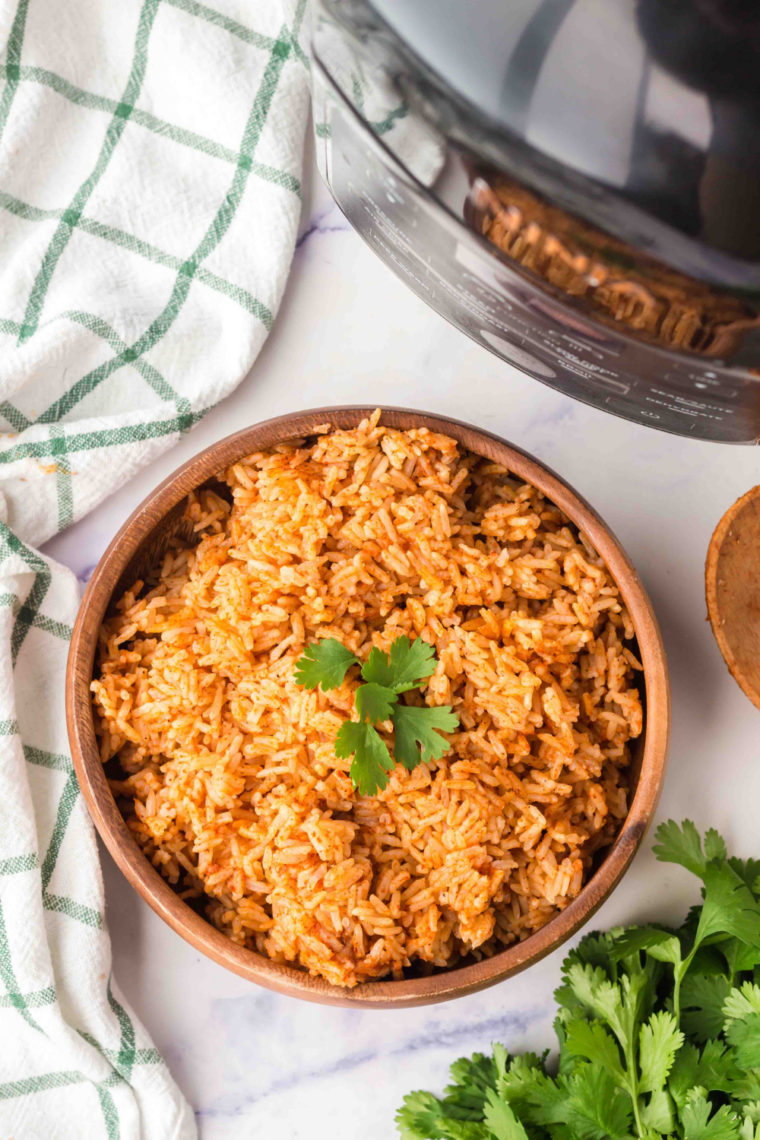 Instant Pot Spanish Rice served in a white bowl with fluffy seasoned rice, diced tomatoes, and green herbs for garnish.