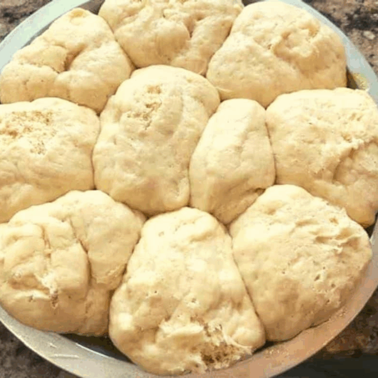 dough balls in pan covered with plastic wrap resting for 30 minutes