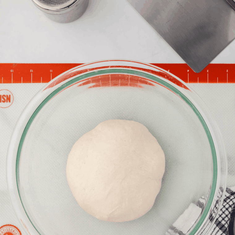 Dividing dough into equal portions and shaping into smooth balls on a greased pan