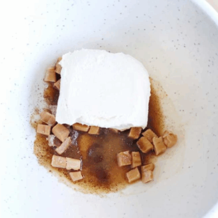 Vanilla extract, softened cream cheese, and chopped apples mixed together in a bowl, ready for air frying.