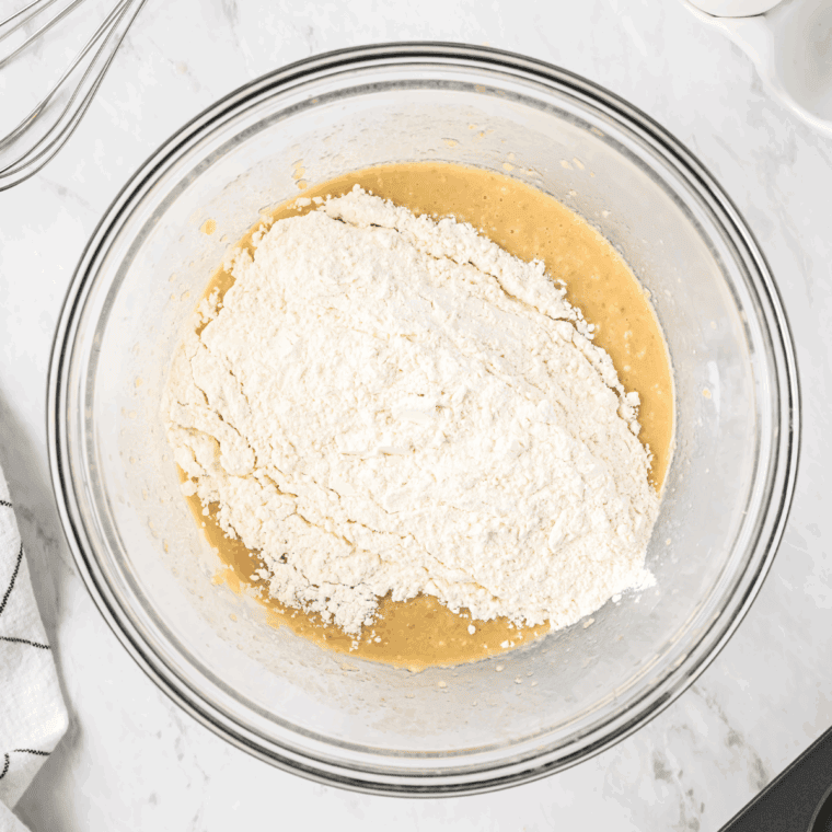Mixing wet and dry ingredients together until just combined with slight lumps visible.