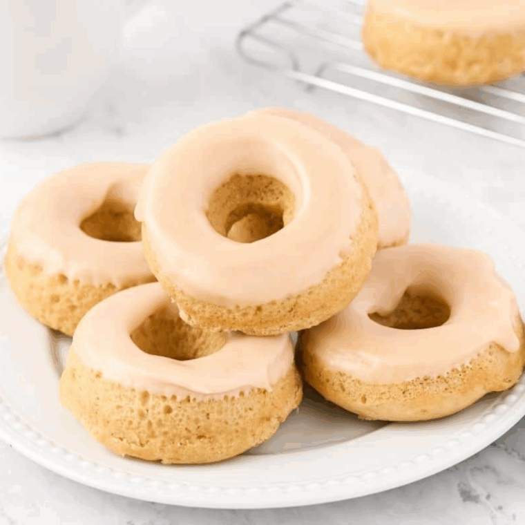Golden air fryer donuts topped with smooth maple frosting, served on a cooling rack.