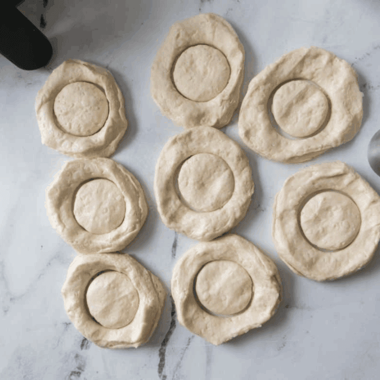 Buttermilk biscuits laid out, with donut centers cut and air fryer basket prepared.