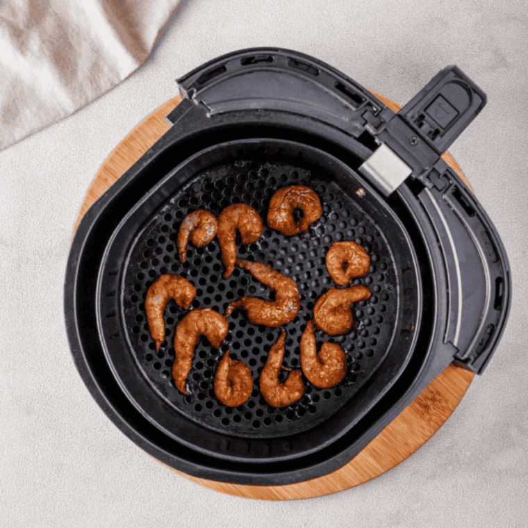Old Bay shrimp skewers cooking in a single layer in the air fryer basket