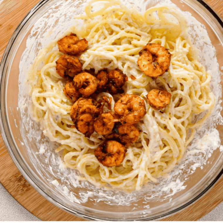 Air fryer Old Bay shrimp tossed with pasta in a white bowl, garnished with parsley