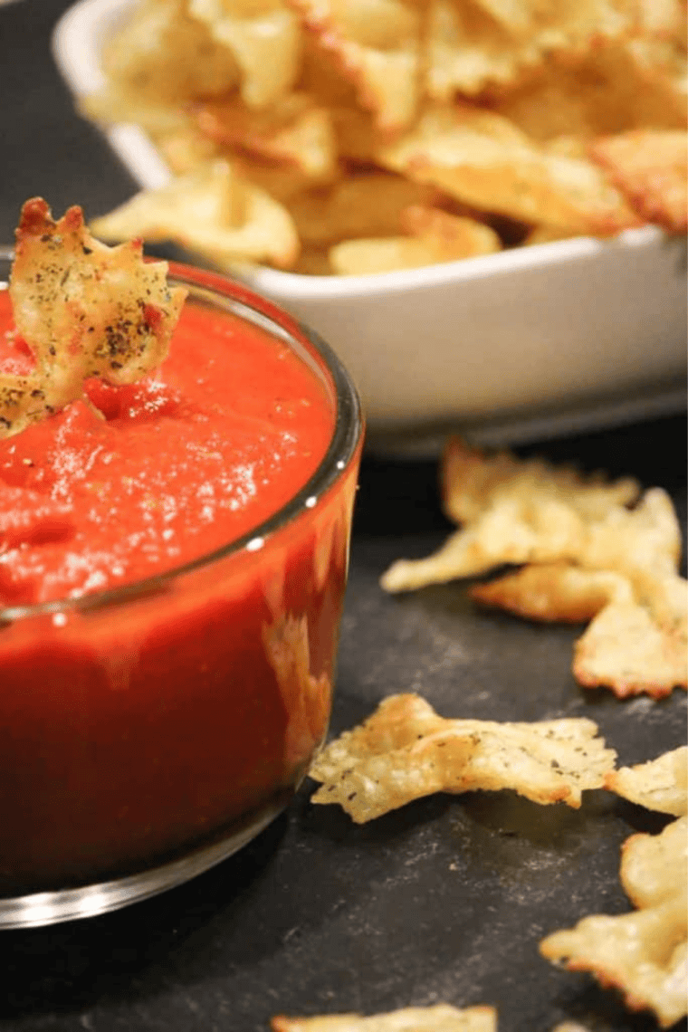 Crispy golden air fryer pasta chips piled in a white bowl with warm marinara sauce on the side.