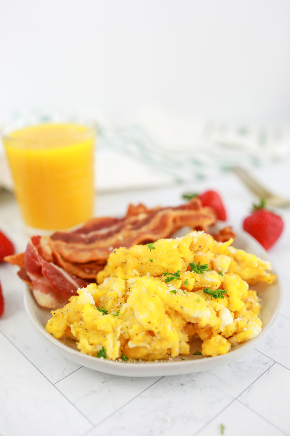 soft scrambled eggs in air fryer being gently stirred with spatula forming curds.