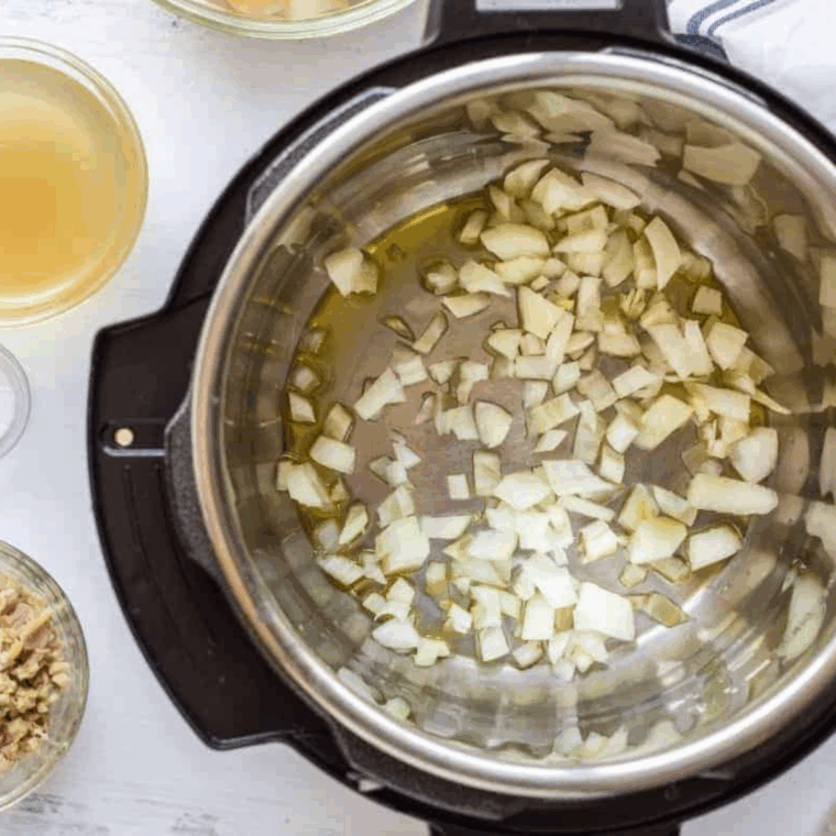 Instant Pot with sizzling chopped bacon cooking on the sauté setting, being stirred with a spoon until crispy, with some pieces set aside for garnish.