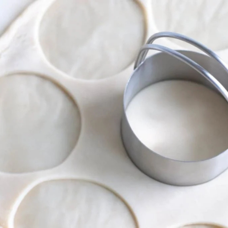 Cutting circles from rolled pie crust with a biscuit cutter on parchment paper