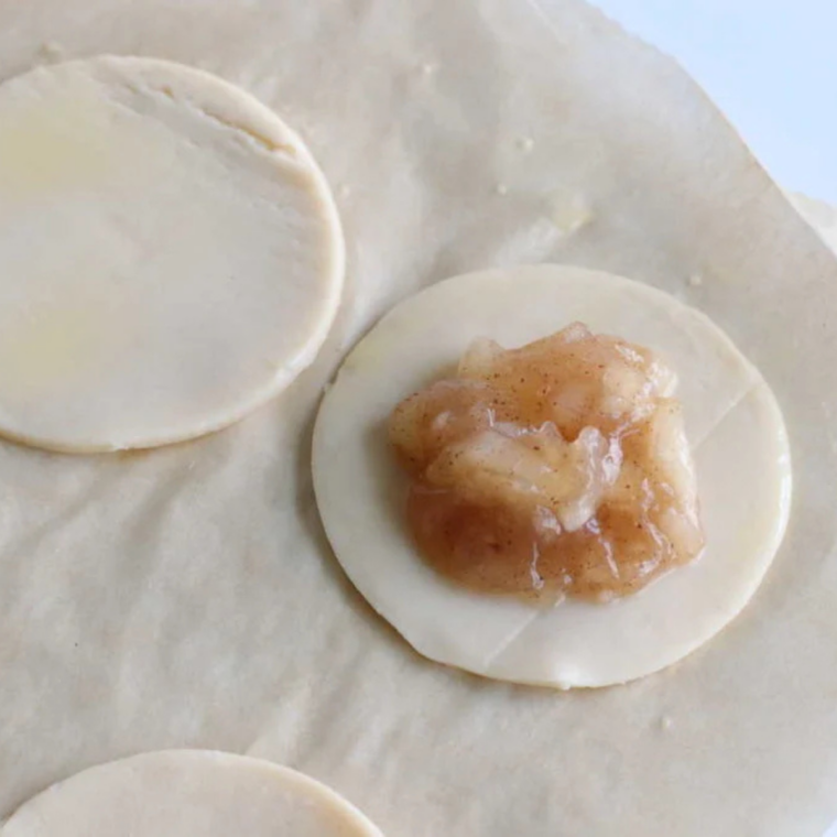 Spooning caramel apple filling into the center of a pie crust circle