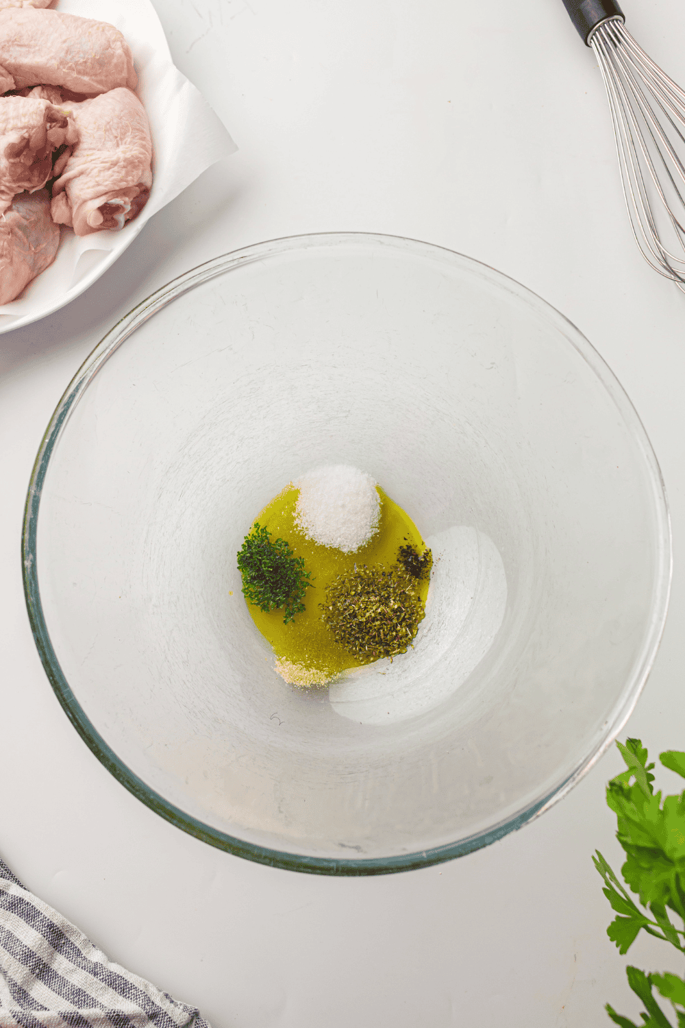 Raw chicken thighs being patted dry with paper towels on a cutting board.