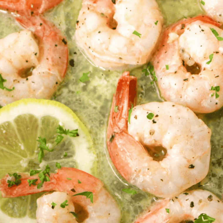 Garlic butter coated shrimp arranged in a single layer in an air fryer basket