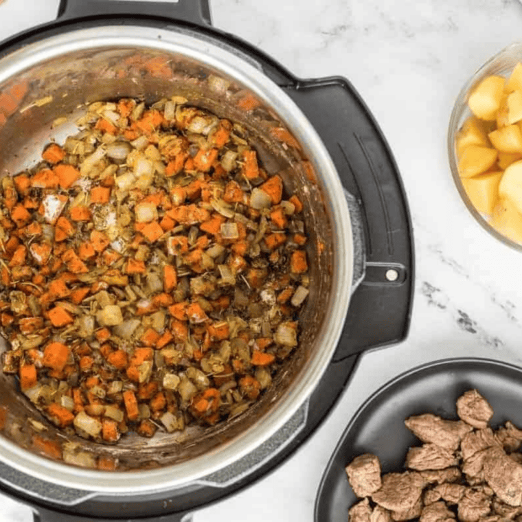 Deglazing the Instant Pot with red wine over sautéed vegetables for beef stew