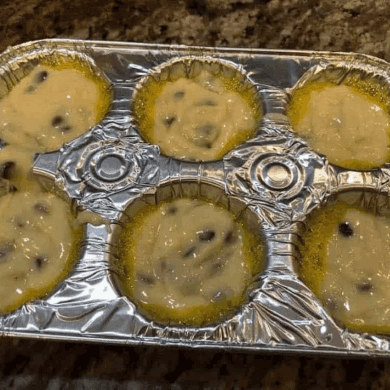 Pouring muffin batter into a greased tin and air frying until fully cooked and golden brown