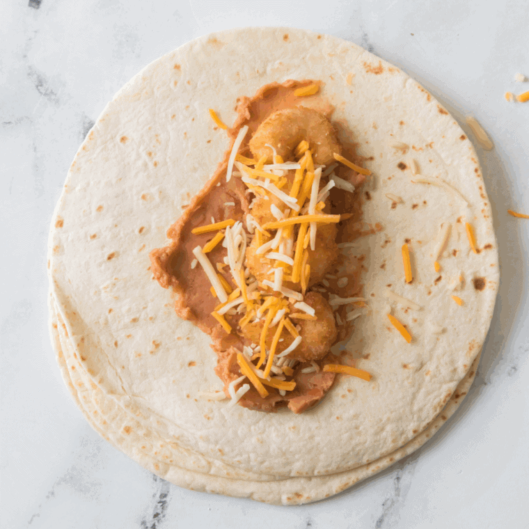 Mix cooked shredded chicken, saut&eacute;ed onions, bell peppers, garlic, shredded cheese, and spices in a medium bowl until fully combined.