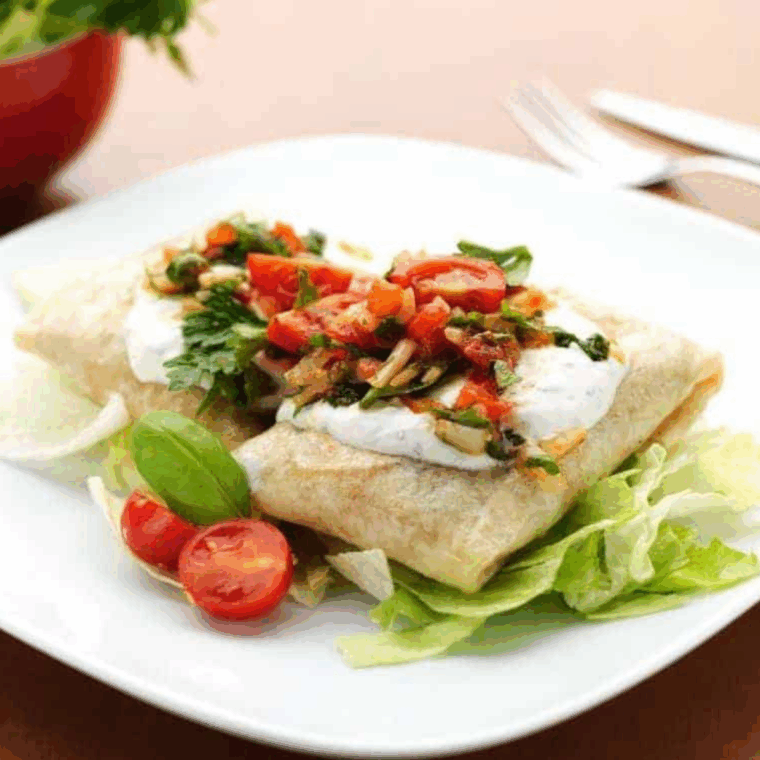 Golden, crispy chicken chimichangas cooked in the air fryer, served on a plate with dipping sauce.