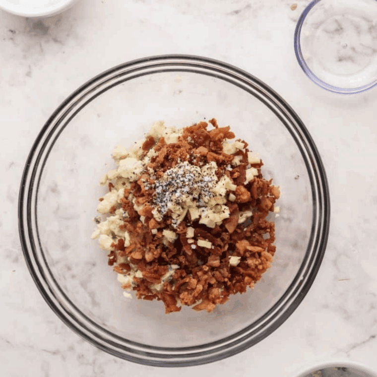 Whisking together bleu cheese, heavy cream, garlic, and bacon bits to make creamy topping