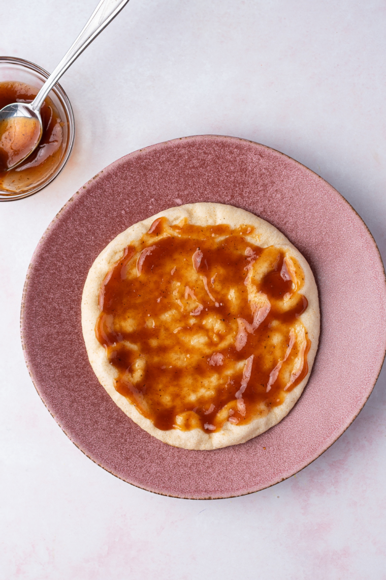 Brushing olive oil onto both sides of a pita bread round with a pastry brush for crispy air fryer pita pizza