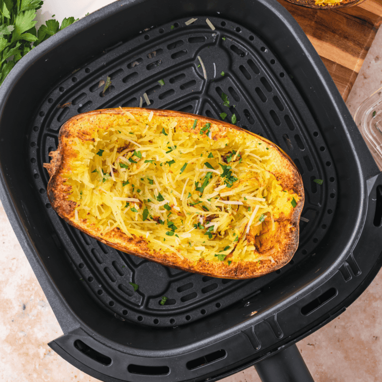 Air fryer spaghetti squash strands fluffed with a fork on a dark red platter