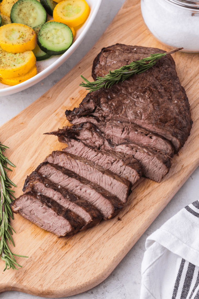 Sliced sirloin steaks drizzled with garlic butter served with mashed potatoes and roasted vegetables.