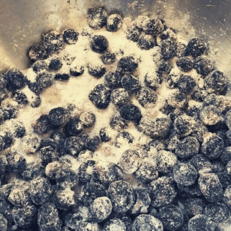 Mixing blueberries with sugar and optional lemon juice or zest, letting them sit to release juices.