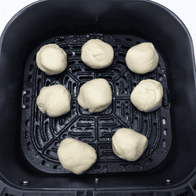 Air fryer basket sprayed and filled with hocus pocus buns ready to cook at 320&deg;F