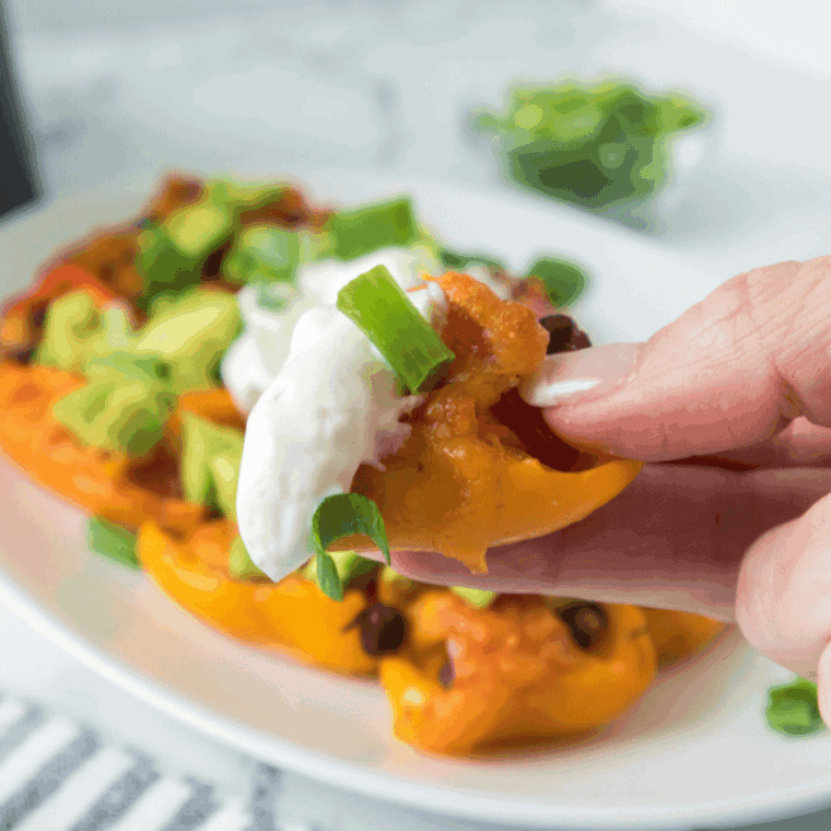 Air fryer mini pepper nachos filled with corn, black beans, cheese, and topped with avocado and green onions