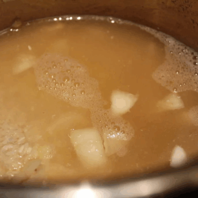 Stirring Jasmine rice, chicken broth, soy sauce, and seasonings into the pot