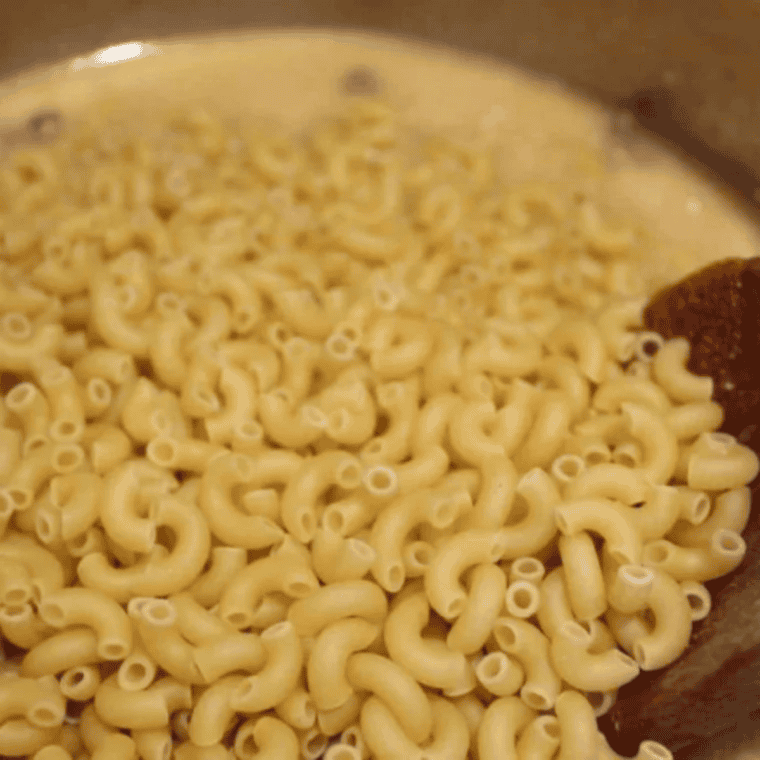Dry elbow macaroni submerged in beef broth over seasoned ground beef in Instant Pot, unstirred