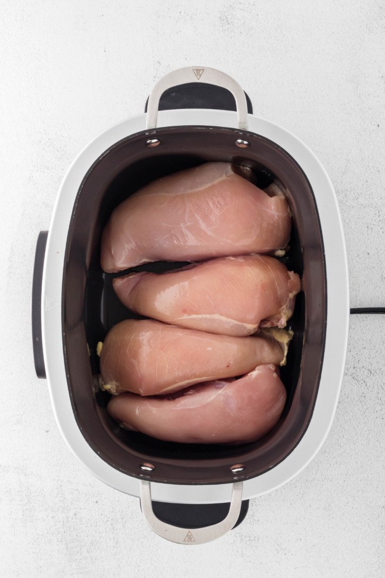 Raw chicken thighs coated in smoky dry rub before going into the slow cooker