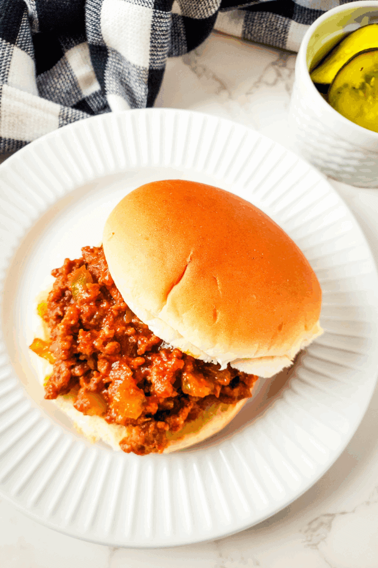 A hearty Pioneer Woman Sloppy Joe sandwich served on a bun with pickles and a side of coleslaw.