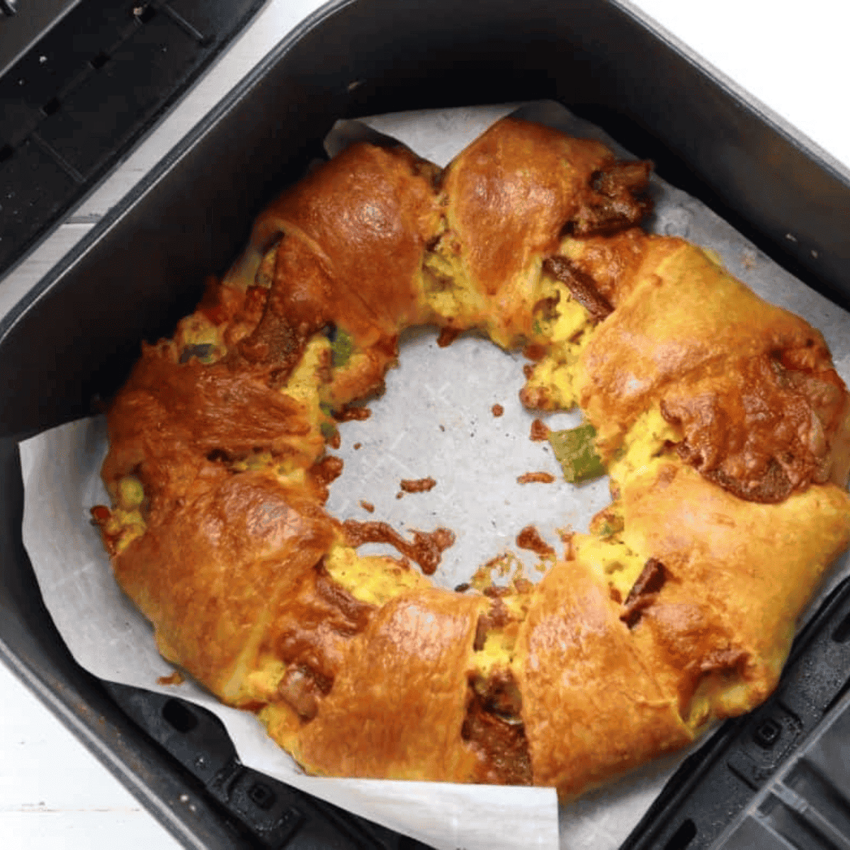 Golden air fryer crescent breakfast ring filled with eggs, cheese, and sausage
