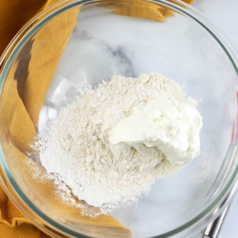 Smooth ball of 2-ingredient Greek yogurt bagel dough on a lightly floured wooden surface