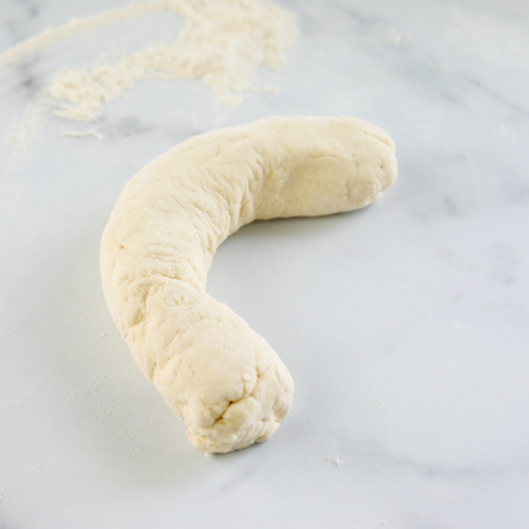 Brushing egg wash onto raw bagels before adding everything bagel seasoning for a golden crust