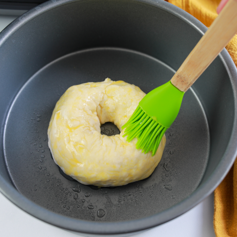 Sprinkling Trader Joe's Everything But the Bagel seasoning over egg-washed bagels in the air fryer basket