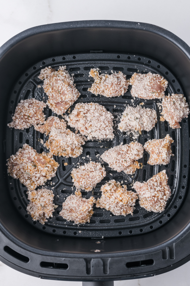 Breaded garlic parmesan chicken bites arranged in a single layer in an air fryer basket
