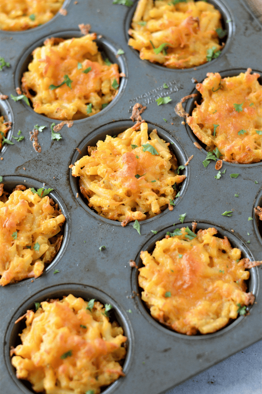 placing muffin tin in air fryer and cooking macaroni and cheese until bubbly