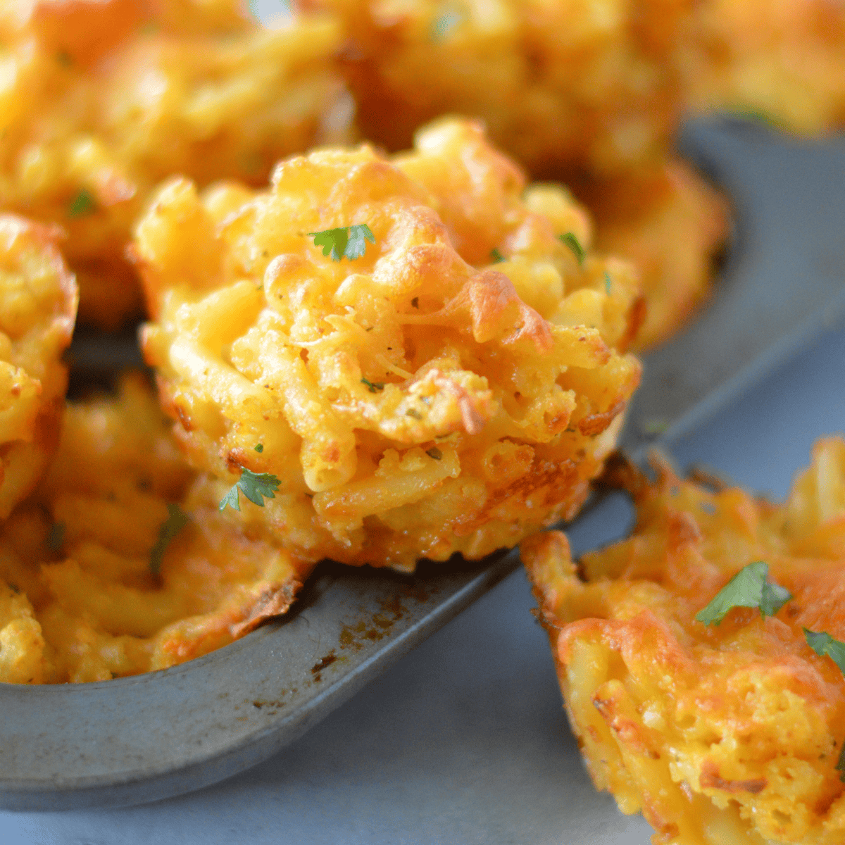 Air fryer macaroni and cheese muffins with golden, crispy edges and a creamy, cheesy center, served fresh from the air fryer basket.
