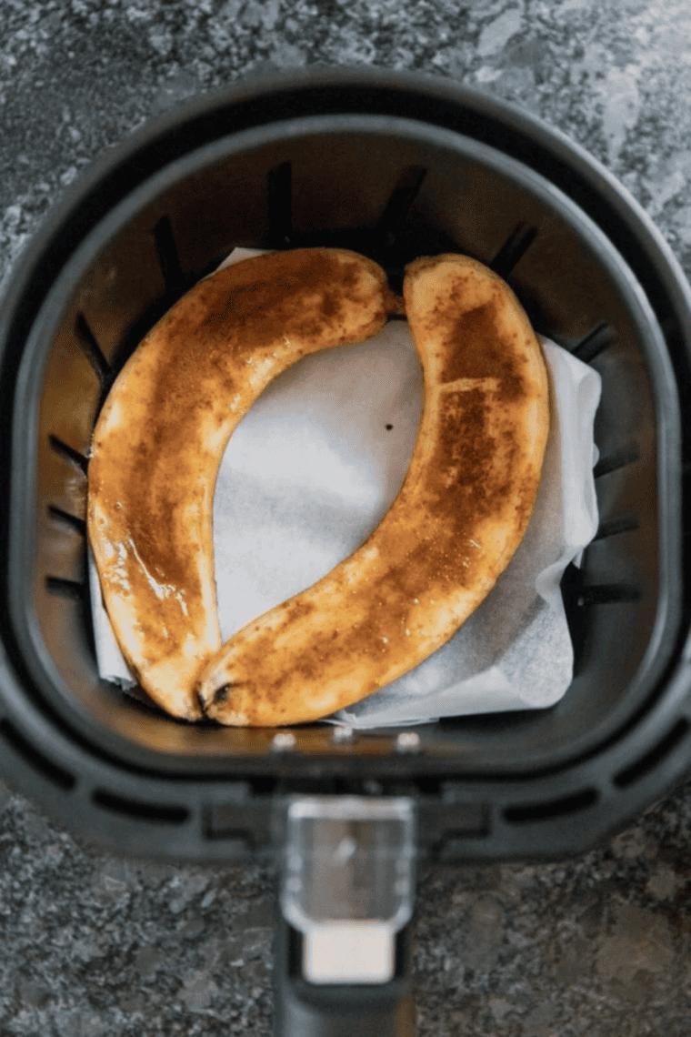 Cinnamon sugar banana halves caramelizing cut-side up in the air fryer basket for bananas foster
