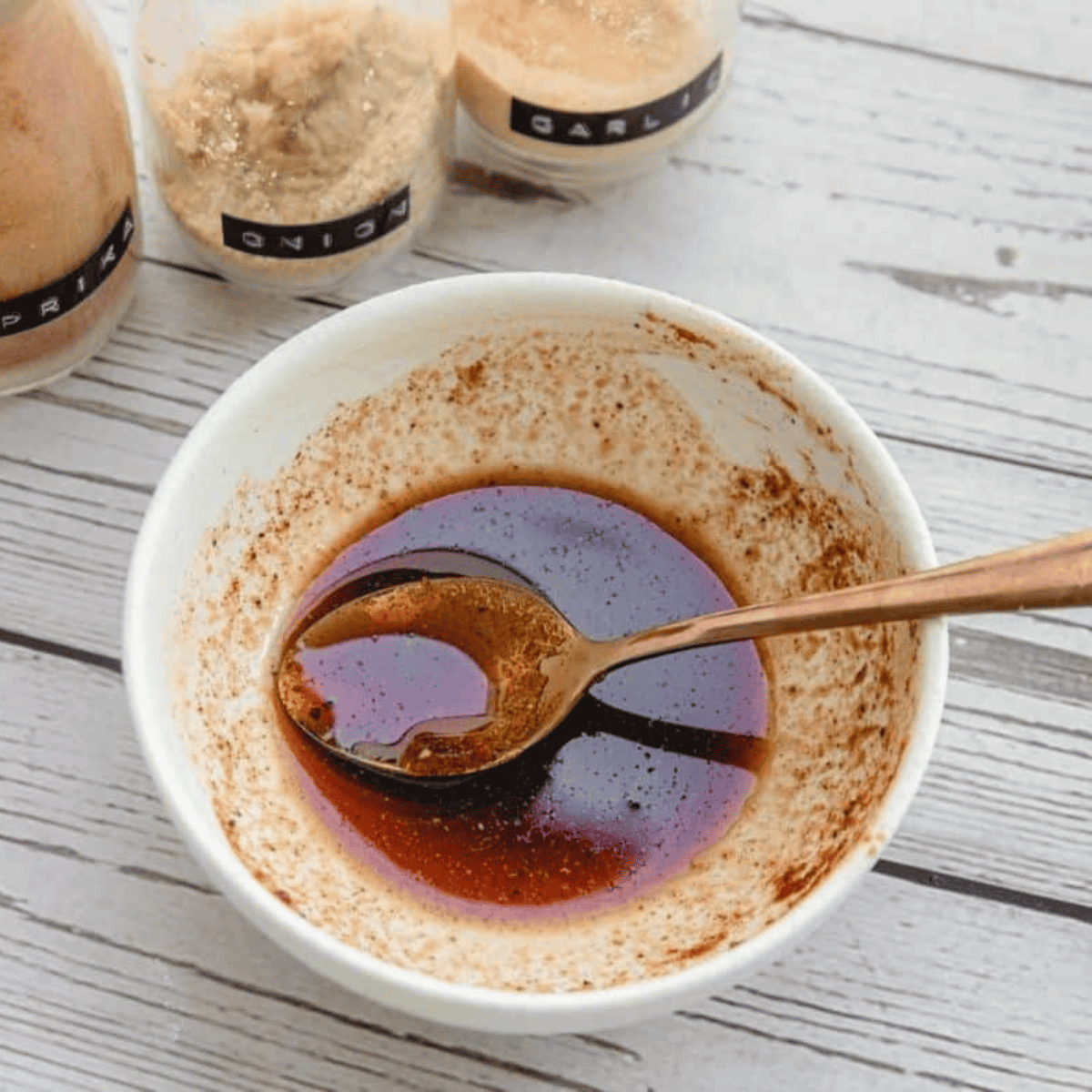 Small bowl filled with maple syrup, soy sauce, and spices ready for carrot bacon marinade.