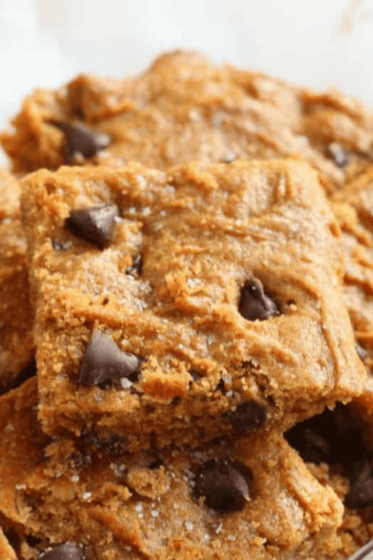 Air fryer peanut butter blondies topped with flaky sea salt on a wooden board